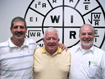 Three men standing in front of a wall with words on it.